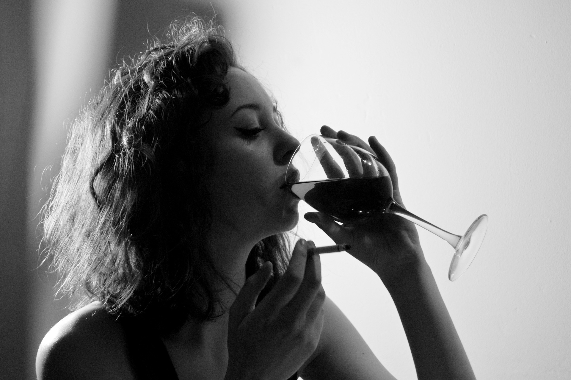 black and white image of woman drinking a large gulp of wine