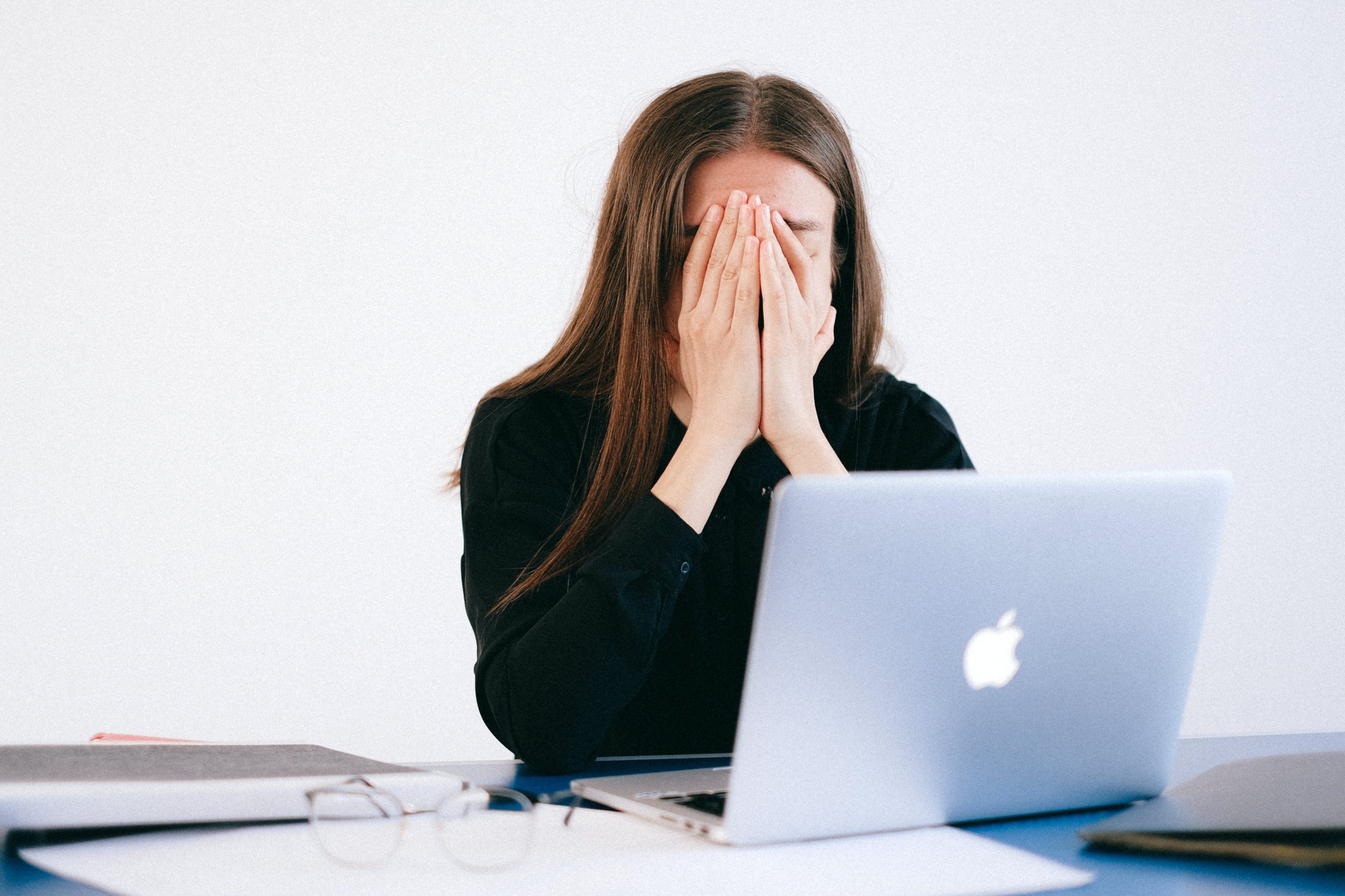 Work related anxiety - woman head in hands in front of laptop